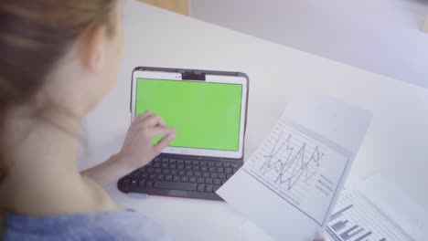 Young-caucasian-woman-in-her-30s-using-her-tablet-to-be-online-with-green-screen