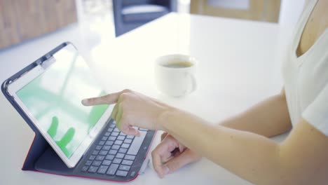 Young-caucasian-woman-in-her-30s-using-her-tablet-to-be-online-with-green-screen