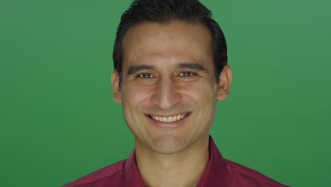 Ethnic-man-nodding-and-smiling,-on-a-green-screen-studio-background