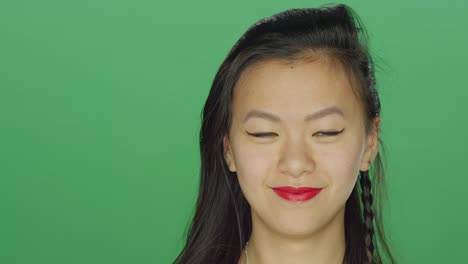 Young-Asian-woman-smiling-and-dancing,-on-a-green-screen-studio-background