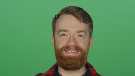 Young-bearded-man-laughs-and-smiles,-on-a-green-screen-studio-background