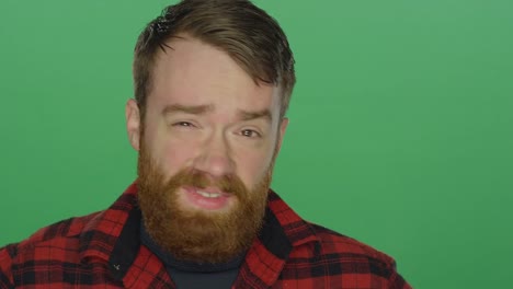 Young-bearded-man-looking-sad-and-worried,-on-a-green-screen-studio-background