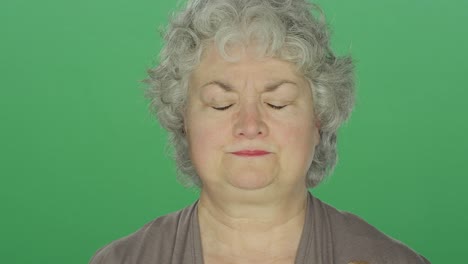 Older-woman-looking-depressed,-on-a-green-screen-studio-background