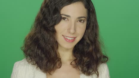 Young-brunette-woman-smiling,-on-a-green-screen-studio-background