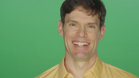 Middle-aged-man-laughing-and-smiling,-on-a-green-screen-studio-background