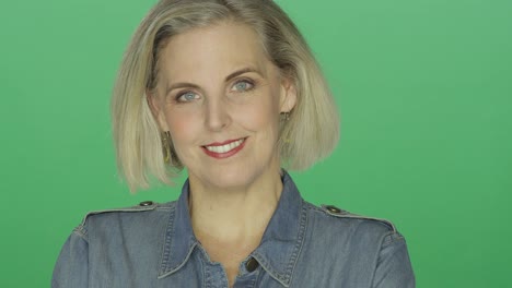 Beautiful-older-woman-smiling-and-being-playful,-on-a-green-screen-studio-background