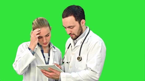 Two-expert-medical-professionals-discuss-a-treatment-for-patient-while-using-their-tablet-on-a-Green-Screen,-Chroma-Key