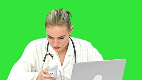 Young-female-doctor-typing-on-laptop,-trying-to-find-a-manual-of-pills-in-the-Internet-on-a-Green-Screen,-Chroma-Key