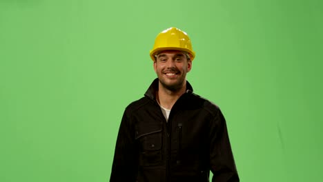 Construction-worker-in-a-hard-hat-is-walking-on-a-mock-up-green-screen-in-the-background.