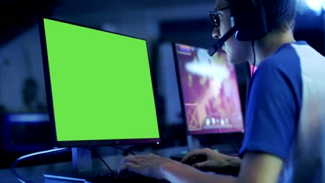 Professionelle-junge-Spieler-spielt-im-Video-Spiel-auf-dem-Green-Screen-Display.-Er-spielt-auf-einer-eSports-Turnier-/-im-Internet-Cafe.-Er-trägt-Kopfhörer-und-Befehle-ins-Mikrofon-spricht.