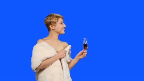 Rubia-encantadora-en-la-capa-de-piel-con-rojo-vino-poses-para-la-cámara-en-fondo-azul