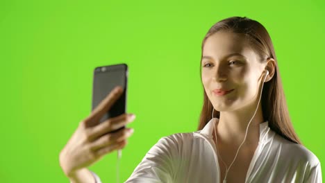 Attractive-girl-young-fashion-model-interract-with-her-smartphone-and-take-selfie-greenscreen-prores-shoot-on-ursa-mini-pro