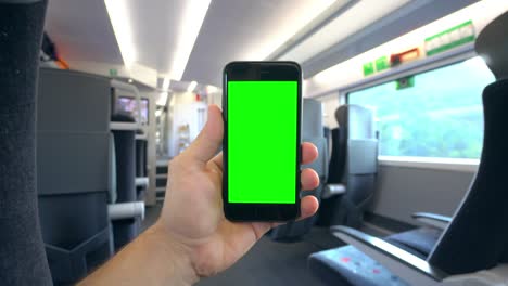 Mano-sosteniendo-un-teléfono-con-una-pantalla-verde-en-el-tren