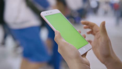 Woman-using-smartphone-with-green-screen-on-the-street.