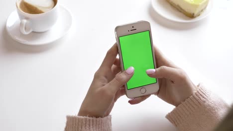 Beautiful-female-hands-using-a-smartphone-in-a-cafe,-green-screen-concept.-60-fps