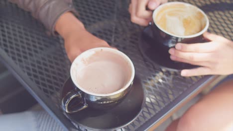 Close-up-of-two-coffee-mugs-on-the-table,-someone-takes-a-drink