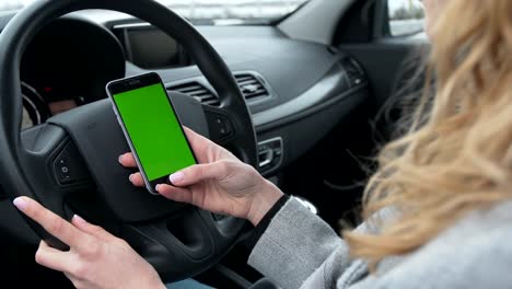 Woman-sits-in-the-modern-car-and-using-smartphone---closeup-hands.-Green-screen.Chroma-key