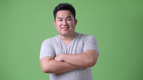 Young-handsome-overweight-Asian-man-against-green-background