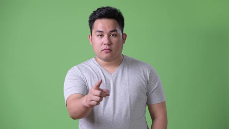 Young-handsome-overweight-Asian-man-against-green-background