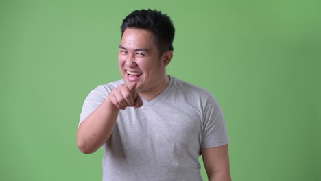 Young-handsome-overweight-Asian-man-against-green-background