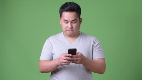 Young-handsome-overweight-Asian-man-against-green-background