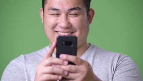 Young-handsome-overweight-Asian-man-against-green-background