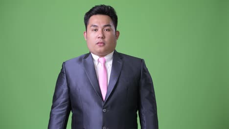 Young-handsome-overweight-Asian-businessman-against-green-background