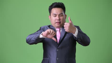 Young-handsome-overweight-Asian-businessman-against-green-background