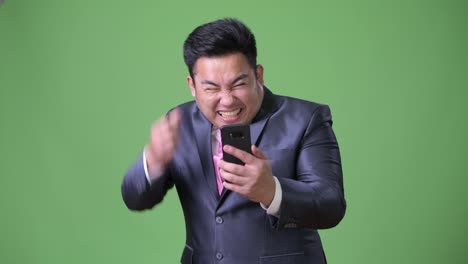 Young-handsome-overweight-Asian-businessman-against-green-background