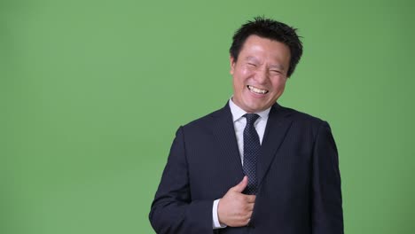 Mature-Japanese-businessman-against-green-background