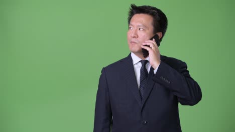 Mature-Japanese-businessman-against-green-background