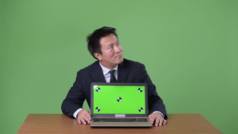 Mature-Japanese-businessman-against-green-background