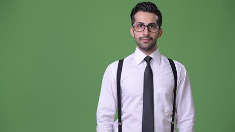 Young-handsome-bearded-Persian-businessman-against-green-background