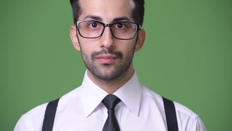 Young-handsome-bearded-Persian-businessman-against-green-background