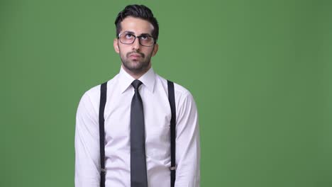 Young-handsome-bearded-Persian-businessman-against-green-background