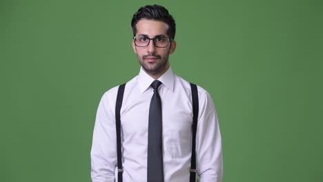 Young-handsome-bearded-Persian-businessman-against-green-background