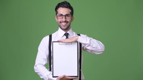 Young-handsome-bearded-Persian-businessman-against-green-background