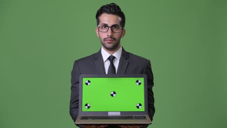 Young-handsome-bearded-Persian-businessman-against-green-background