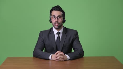 Young-handsome-bearded-Persian-businessman-against-green-background