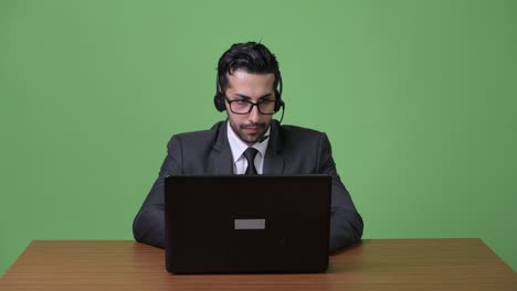 Young-handsome-bearded-Persian-businessman-against-green-background