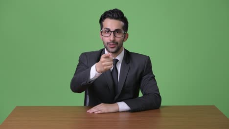 Young-handsome-bearded-Persian-businessman-against-green-background