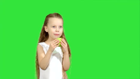 Portrait-of-a-little-girl-eating-green-apple-on-a-Green-Screen,-Chroma-Key