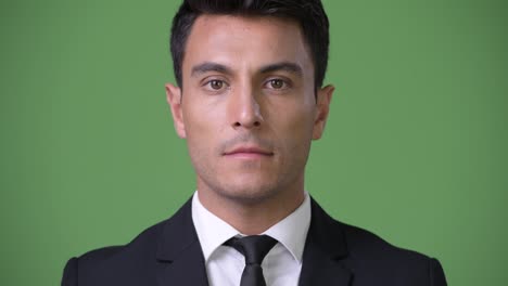 Young-handsome-Hispanic-businessman-against-green-background