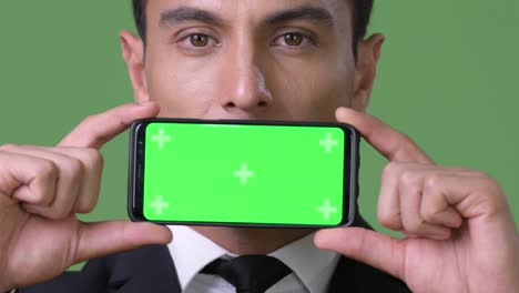 Young-handsome-Hispanic-businessman-against-green-background