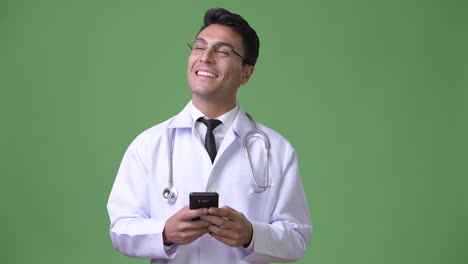 Young-handsome-Hispanic-man-doctor-against-green-background