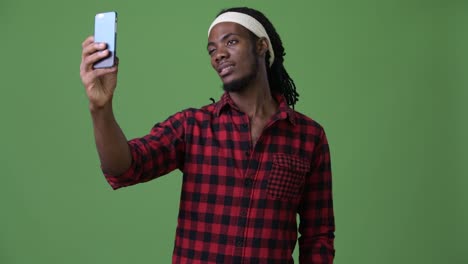 Young-handsome-African-man-with-dreadlocks-against-green-background