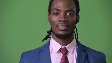 Young-handsome-African-businessman-with-dreadlocks-against-green-background