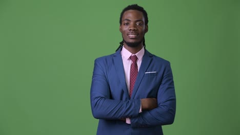 Young-handsome-African-businessman-with-dreadlocks-against-green-background