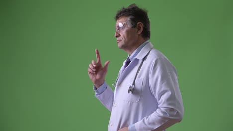 Mature-handsome-man-doctor-against-green-background