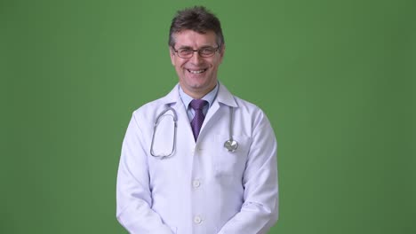 Mature-handsome-man-doctor-against-green-background